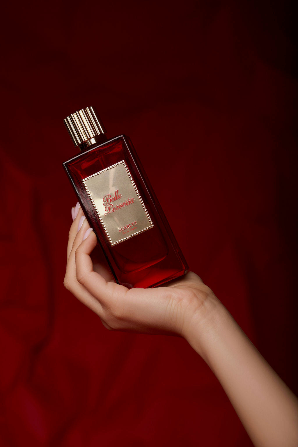 Daisy Marquez of Bella Perversa holding her signature scent, Scarlet Eau de Parfum, cradled in her hand.